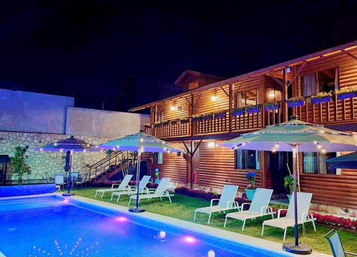 Cabañas y alberca iluminadas de noche con luces cálidas