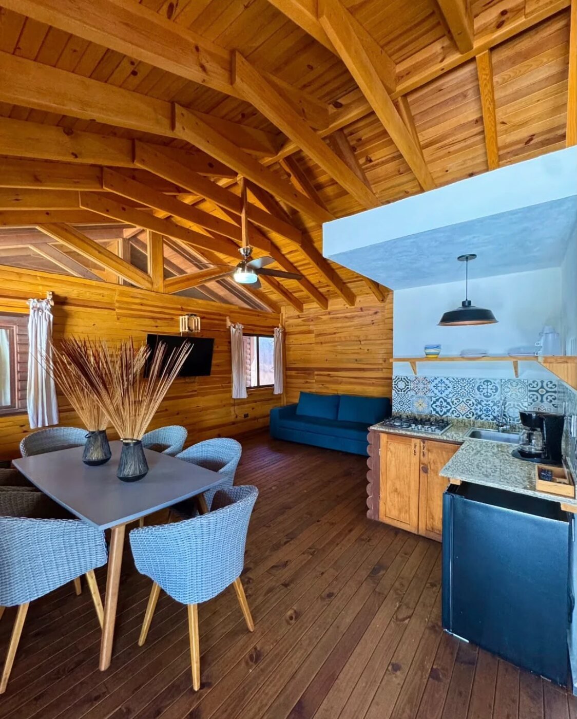 Interior de cabaña con sala, comedor y cocina de madera